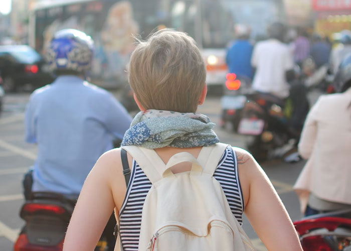 Person over 40 with backpack and scarf in urban setting, representing childfree lifestyle and life choices reflection.