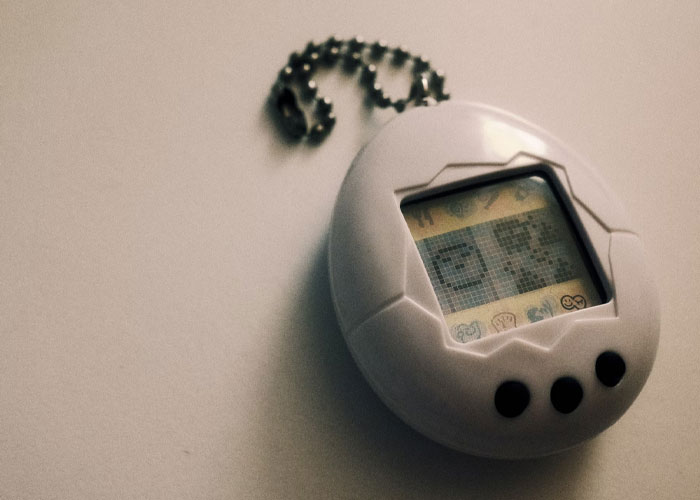 Retro digital pet device on a chain, representing nostalgic people confessing things they didn't know late in life.