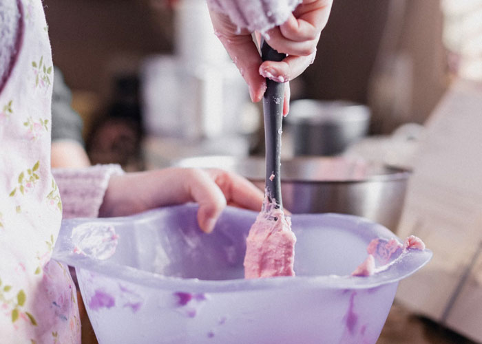 Person mixing pink frosting in a bowl, illustrating everyday things people confess they didn't know until embarrassingly late in life.
