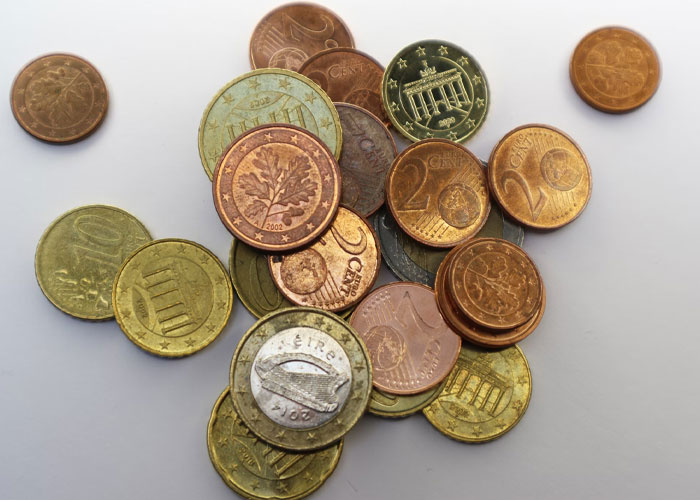 Assorted euro coins scattered on a white surface representing money people didn't know until embarrassingly late in life.