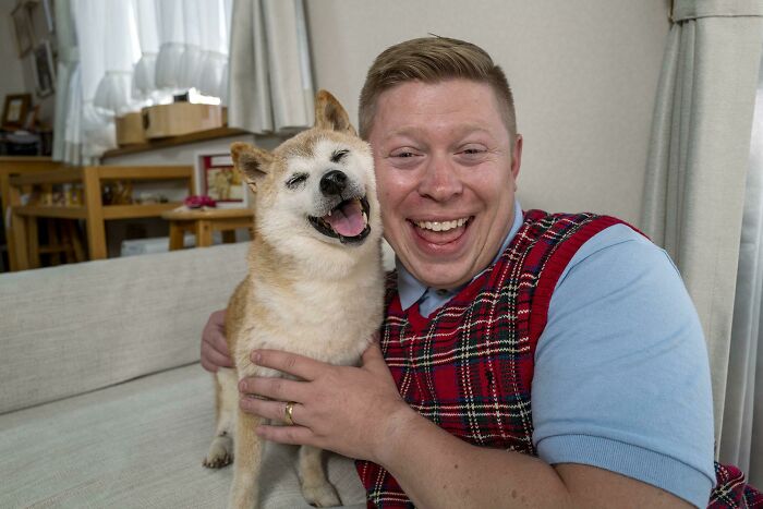 Man smiling and hugging one of the cutest dogs ever in a cozy living room setting with natural light.