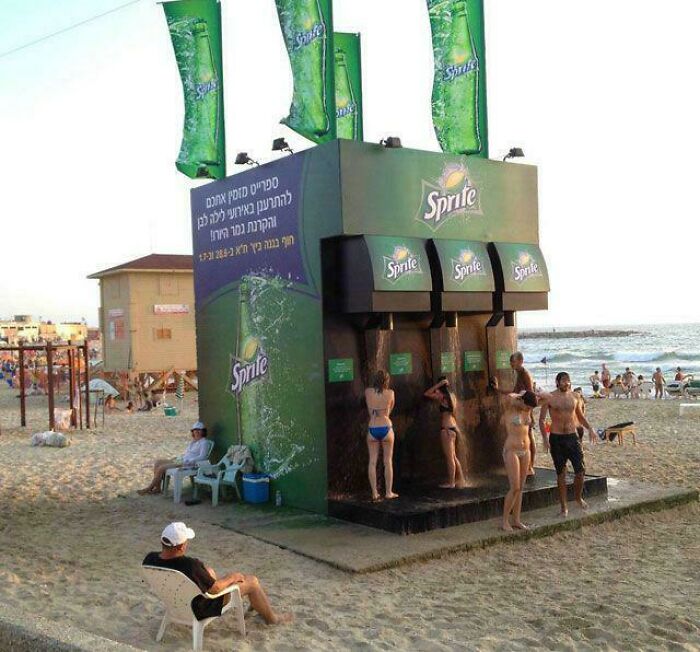 Creative Sprite advertisement on a beach with people cooling off under giant soda dispenser showers.