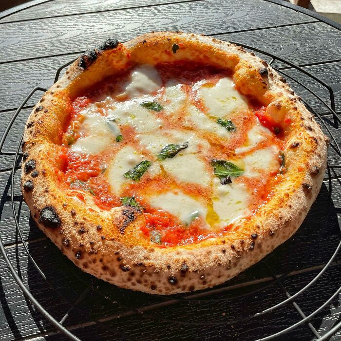 Perfectly cooked Margherita pizza with melted cheese and fresh basil, showcasing food perfection and delicious craftsmanship