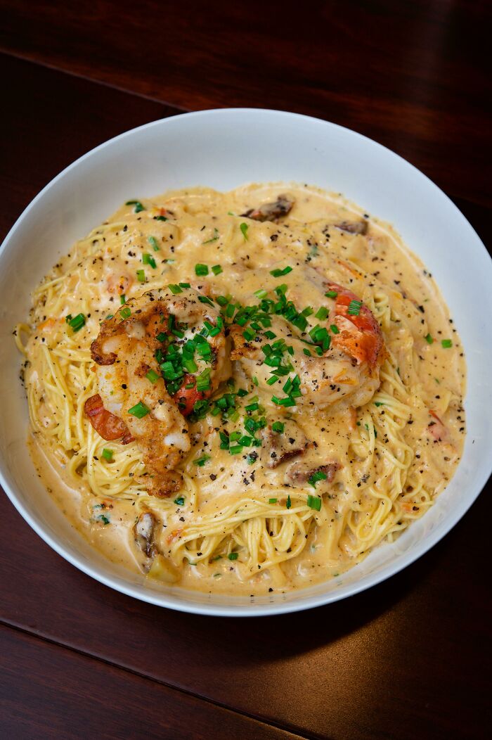 Creamy pasta with grilled shrimp and fresh herbs, showcasing perfection in food presentation and texture.