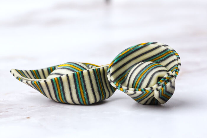 Close-up of striped, colorful pasta shells showcasing perfection in food preparation on a white marble surface.