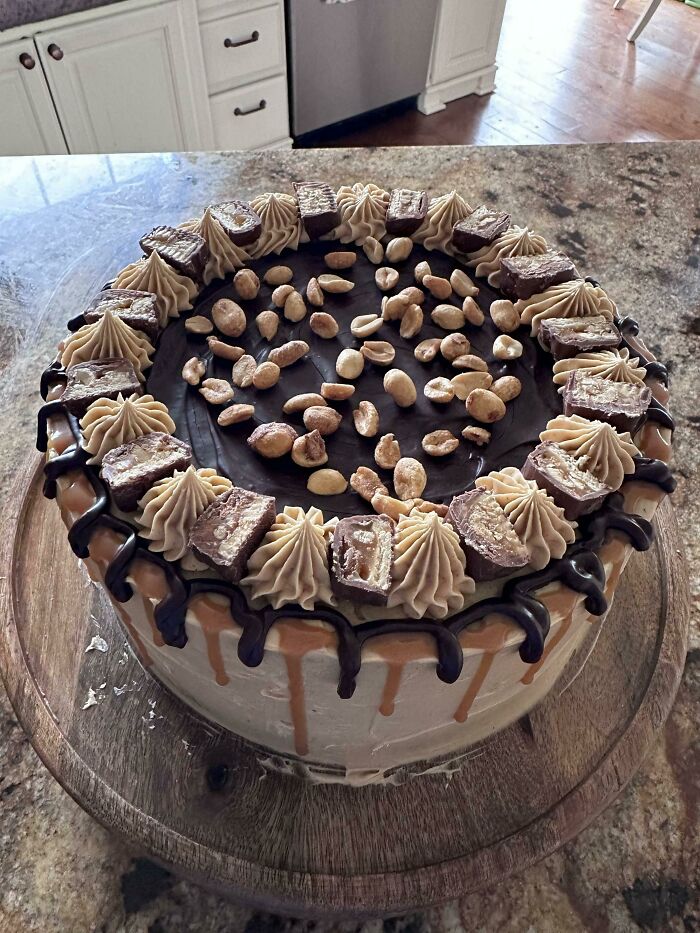 Chocolate peanut butter cake with perfect frosting, peanut topping, and candy pieces showcasing food perfection.