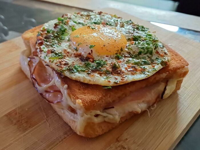 Perfectly cooked sandwich with melted cheese, ham, and a seasoned fried egg, showcasing food perfection and culinary skill.