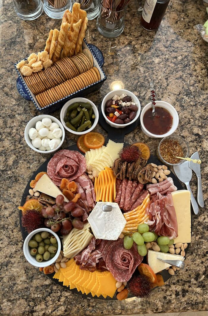 Charcuterie board with various cheeses, meats, olives, grapes, and crackers showcasing perfection in food presentation.