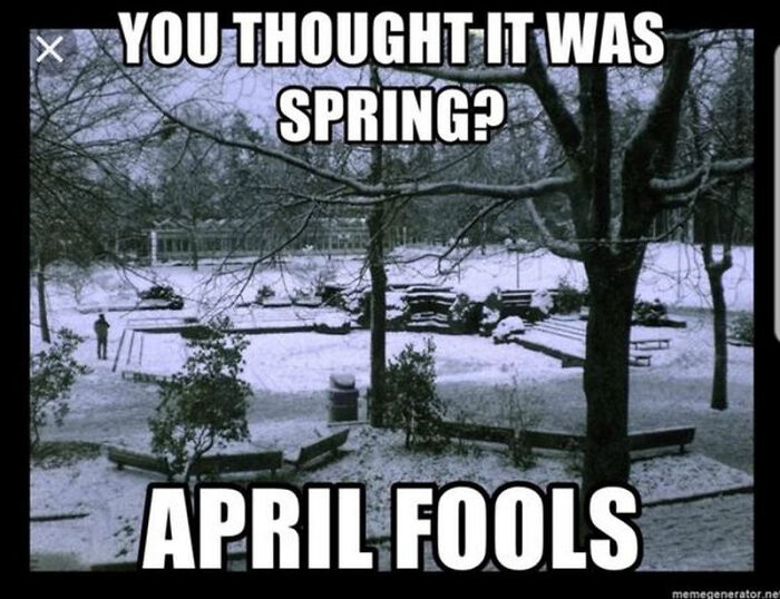 Snow-covered park with trees and benches, text reads "You thought it was spring? April Fools"—funny spring meme.