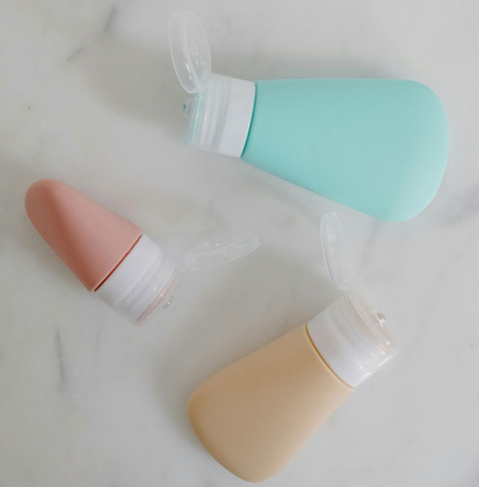 Travel-sized silicone bottles on a white surface, showcasing sleek design for portable skincare products.