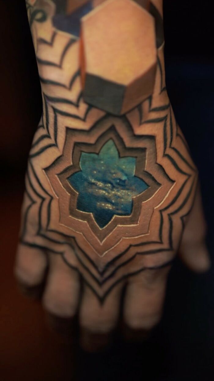 A mind-bending tattoo on a hand, featuring geometric and ocean motifs.
