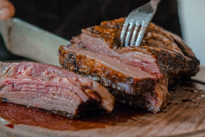 Close-up of juicy grilled steak being sliced with a fork and knife showcasing unfiltered food opinions on crunchy vinegar.