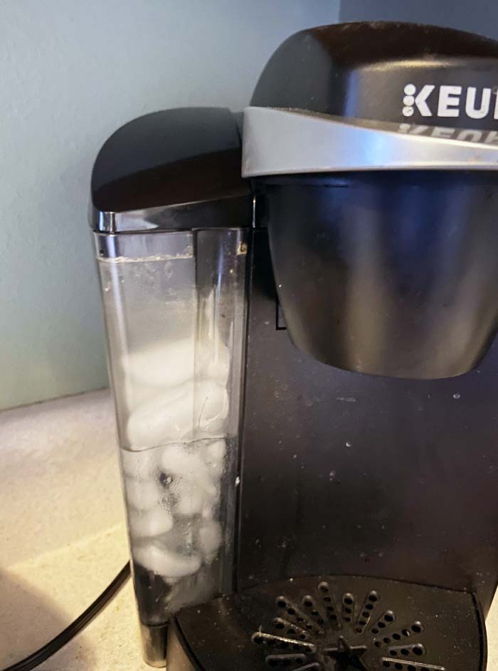 Coffee maker with ice cubes in the water reservoir, a clueless mistake surprising others with its stupidity.