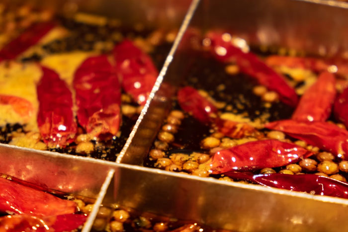Close-up of crunchy vinegar with red chili peppers and spices in a divided metal container representing unfiltered food opinions.