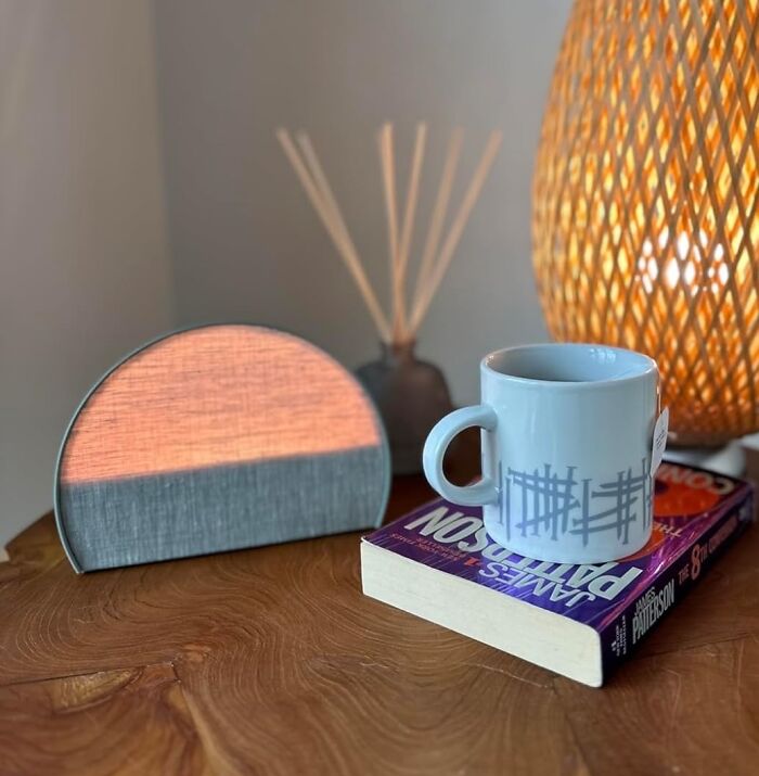 Cozy home decor on wooden table with lamp, book, mug, and ambient light. Shopping list inspiration for awesome things.