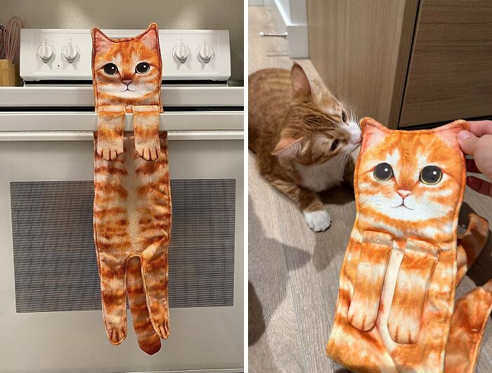 Cat-shaped kitchen towel hanging on oven and a real cat sniffing it on the floor.