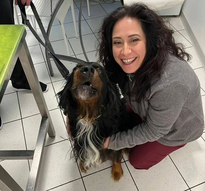 Smiling woman embraces happy dog at a veterinarian's office, capturing a wholesome moment.