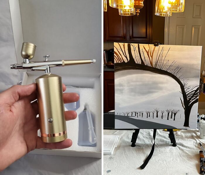 Airbrush tool in hand next to a tree landscape painting on an easel, ideal for artistic souls.