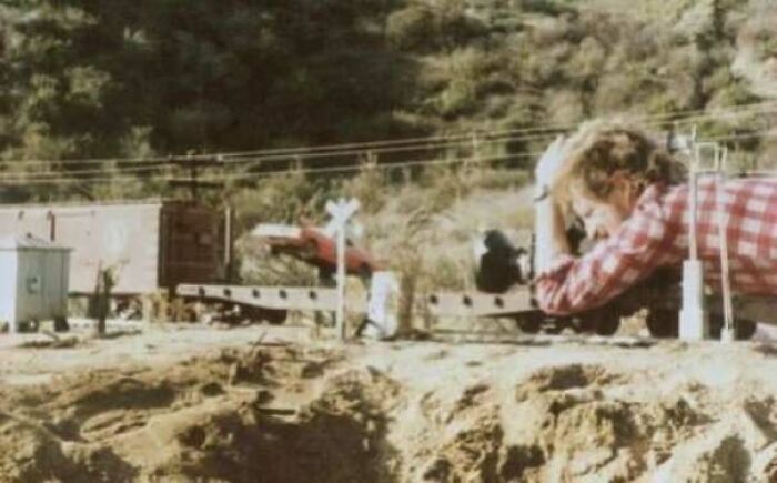 Person photographing miniature train setup outdoors, providing new perspective on famous scenes.