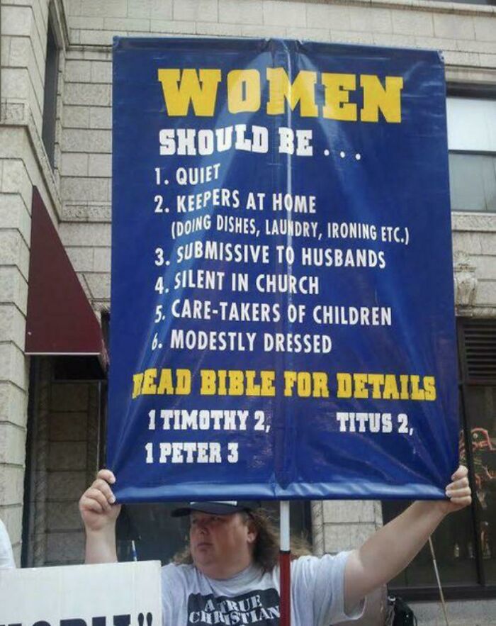Man holding a sign listing traditional and submissive roles for women, highlighting cringe-worthy views on women.