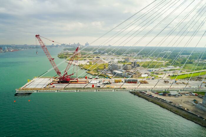 Aerial view of brilliant infrastructure showing a cable-stayed bridge under construction over a body of water.