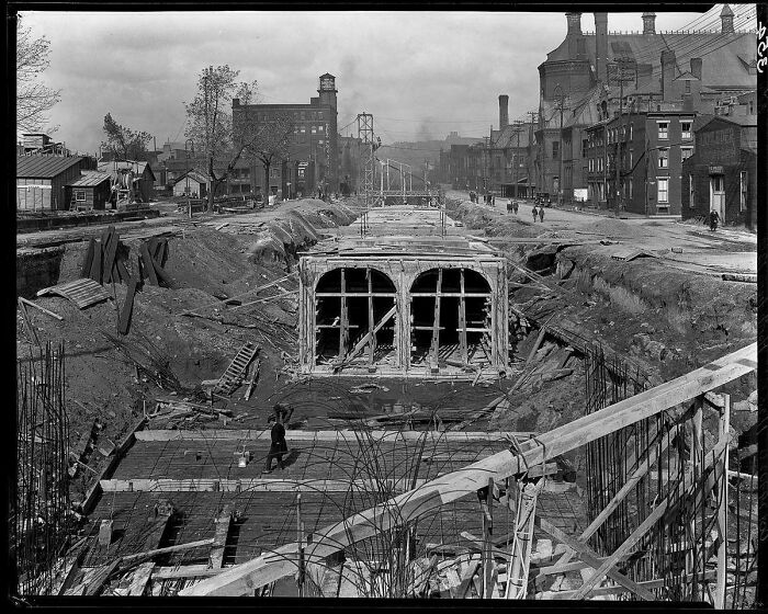 Early 20th-century urban construction site showing brilliant infrastructure development with tunnels and industrial buildings.
