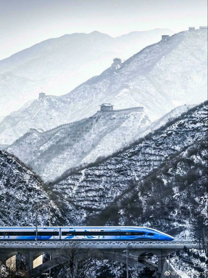 High-speed train crossing a snowy mountainous region showcasing brilliant infrastructure in winter landscape.