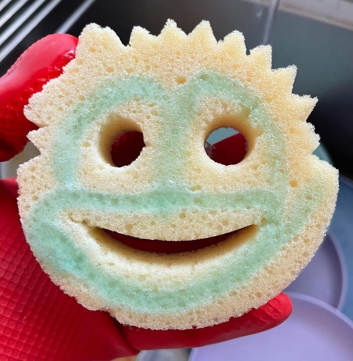 Smile-shaped sponge in a red-gloved hand, perfect for a lazy deep clean of your home.
