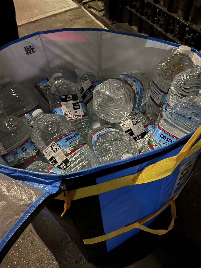Large bag filled with multiple bottled water containers on the street