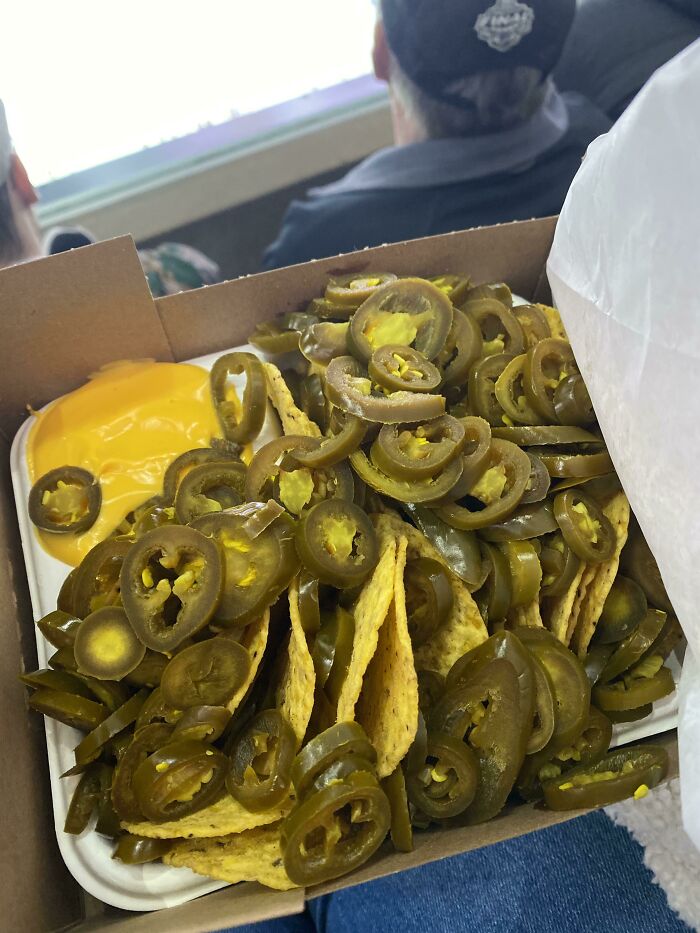 Nachos generously topped with extra jalapeños and cheese, served at a stadium.