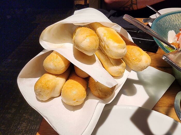 A stack of extra breadsticks on a restaurant table, showcasing food service workers' compliance with customer requests.