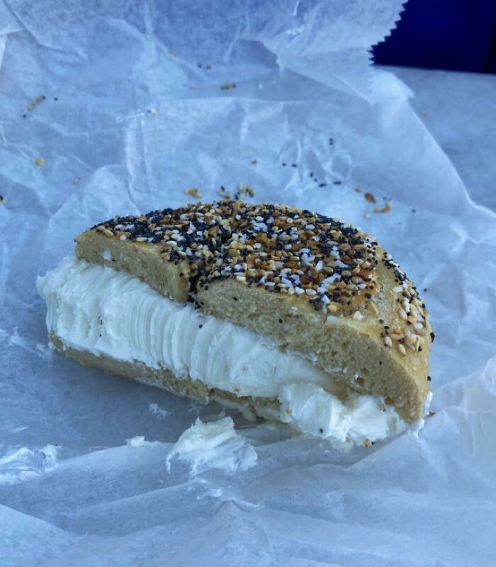 Bagel with extra cream cheese, showcasing food service workers complying with customer requests.