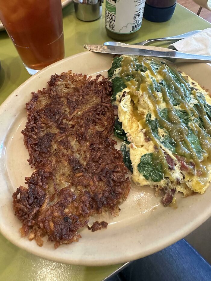 Extra hash browns and a loaded omelette on a diner plate, showcasing a delicious compliance with a customer's food request.