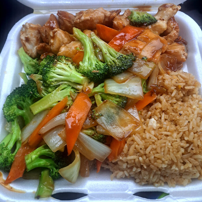 Takeout box with extra vegetables, chicken, and rice, fulfilling a customer's request for additional toppings.