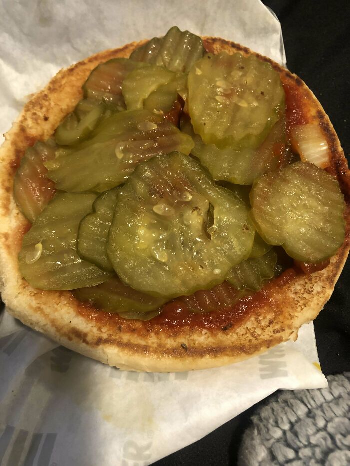 Burger with extra pickles on a bun, showing deliciously complied customer request in food service.