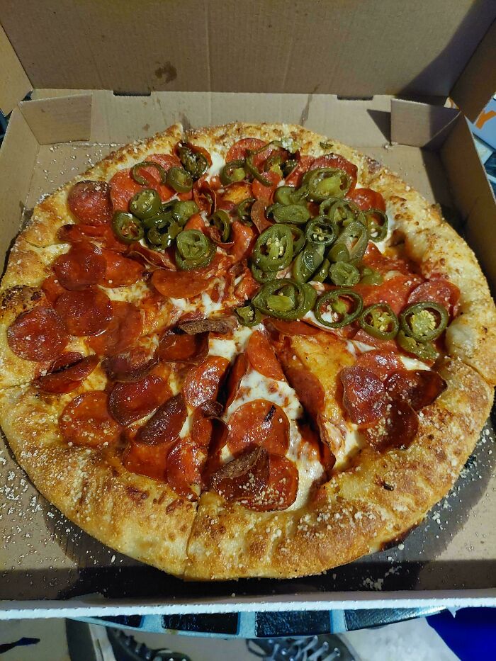 Pizza with extra pepperoni and jalapeños in a box, showcasing food service workers' delicious compliance with requests.