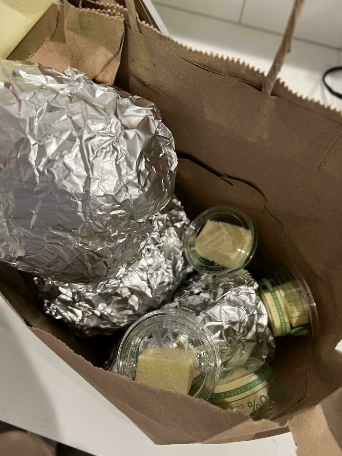 Extra cheese cups and foil-wrapped food in a brown paper bag.