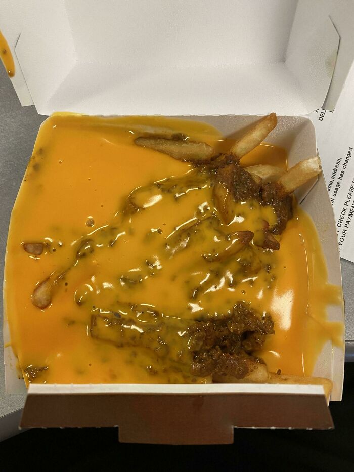 Fries drenched in cheese sauce and chili, showcasing food service compliance with a customer's extra request.