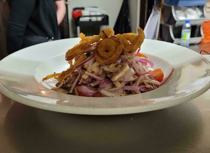 Delicious compliance with a customer request: a dish topped with extra onions and garnishes in a restaurant setting.