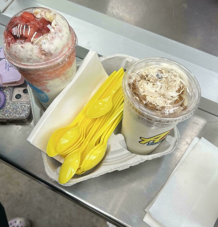 Extra spoons with two creamy drinks, fulfilling a customer request in food service.
