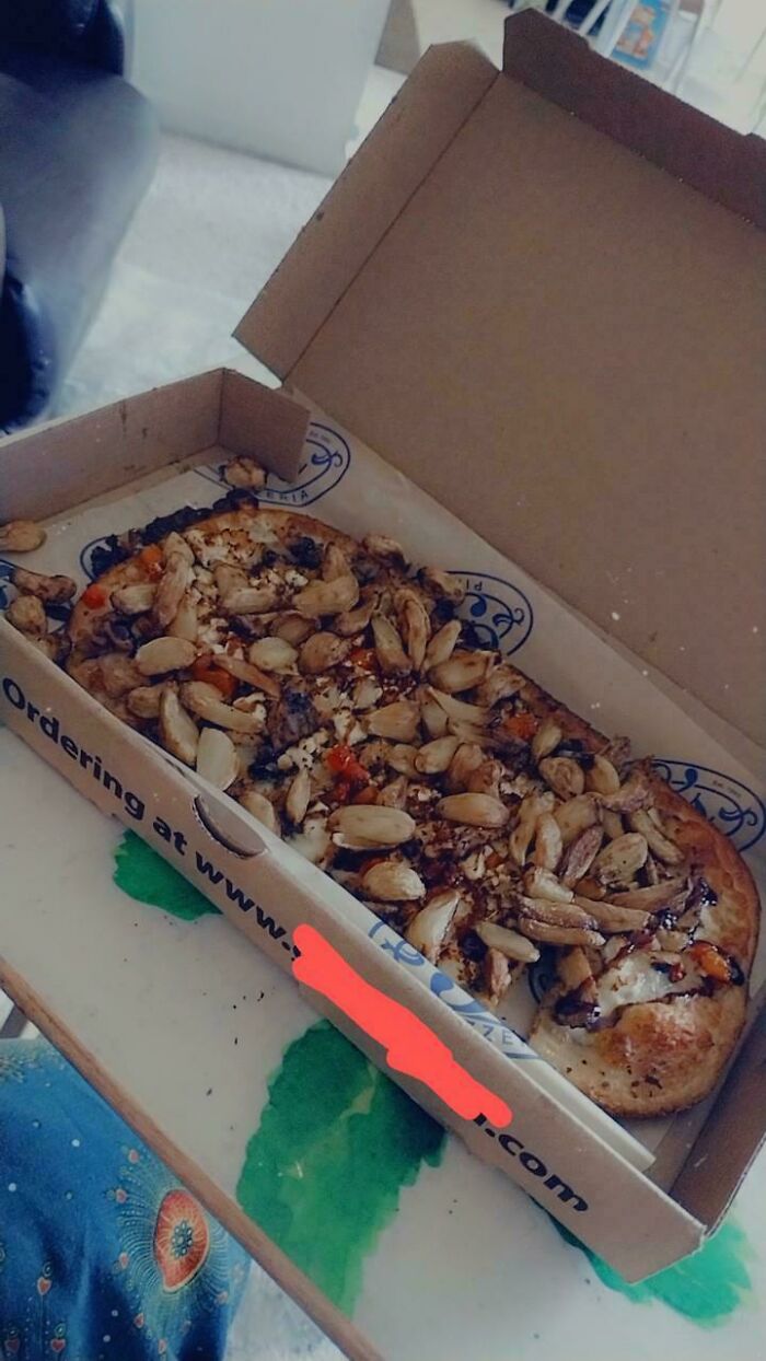 Pizza loaded with extra garlic cloves in an open takeout box, showcasing food service worker compliance.