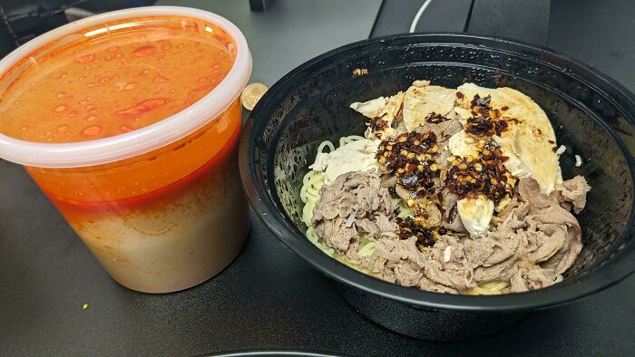 Bowl of noodles with beef and chili, served alongside extra sauce, showcasing food service workers complying with customer requests.