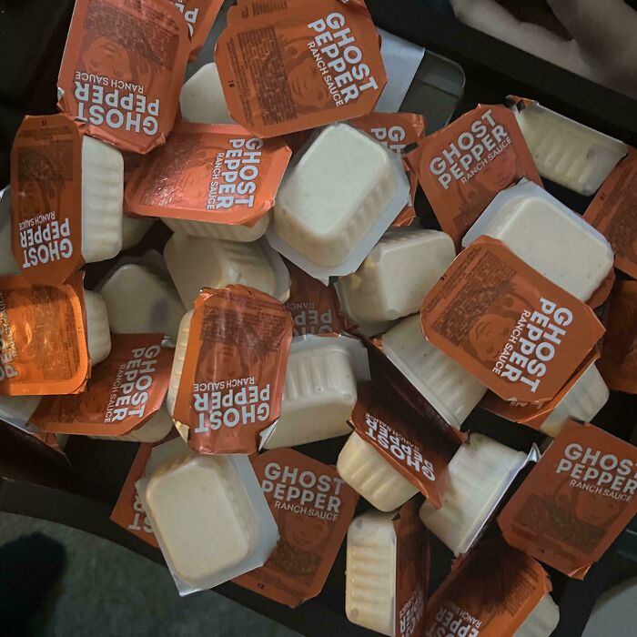 A pile of extra Ghost Pepper ranch sauce packets, illustrating food service workers fulfilling customers' requests.