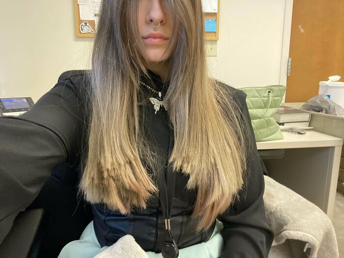 Person with long hair showing uneven haircut in a casual setting, highlighting a hair accident.