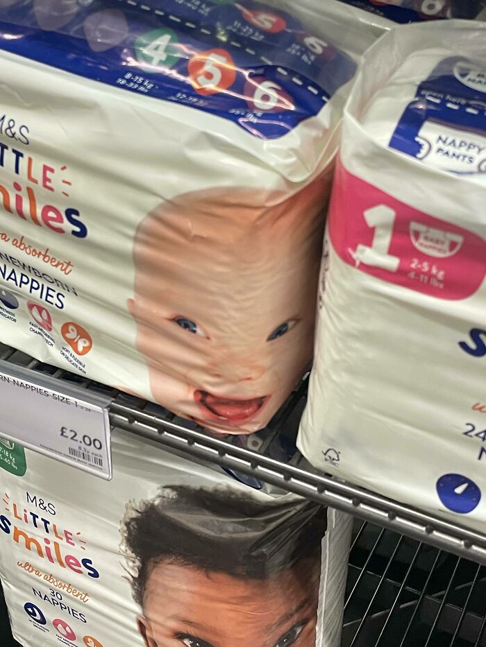 UK humor: Baby face printed comically on a pack of M&S Little Smiles nappies in a British store display.