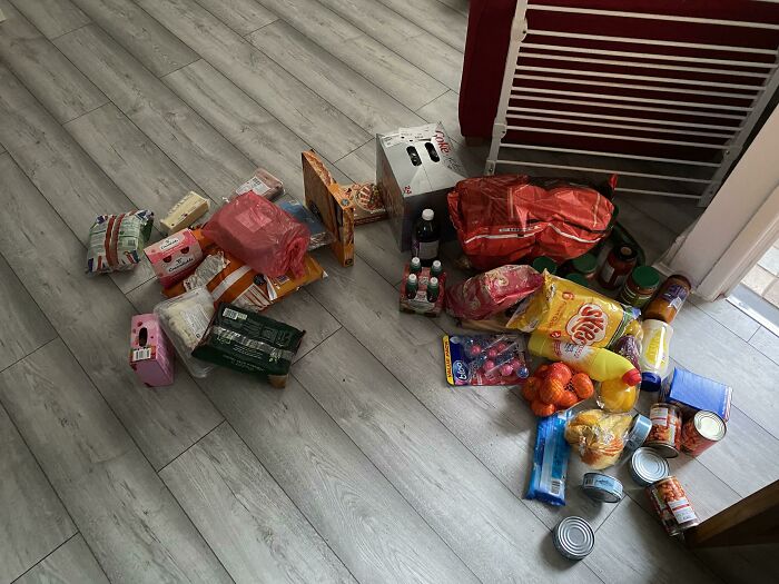 Groceries scattered on a kitchen floor, featuring various British snack items and canned goods.