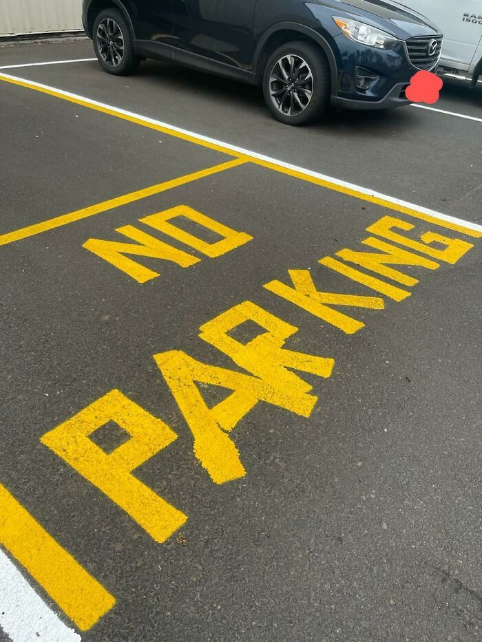 Parking fail with a car parked over "no parking" sign on asphalt.