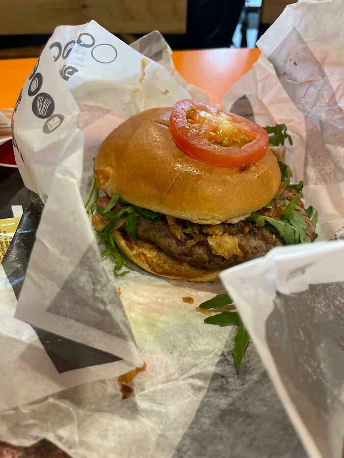 Burger with a misplaced sliced tomato on top, highlighting a hilarious fail.