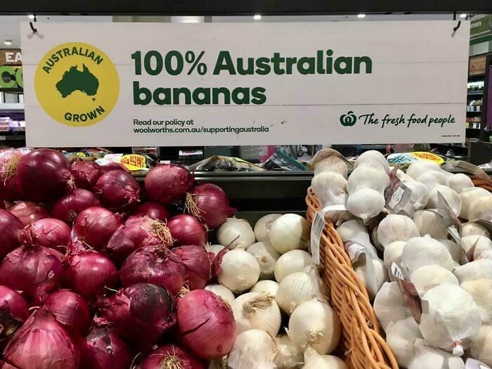Sign reads "100% Australian bananas" above onions and garlic display, showcasing a humorous fail.