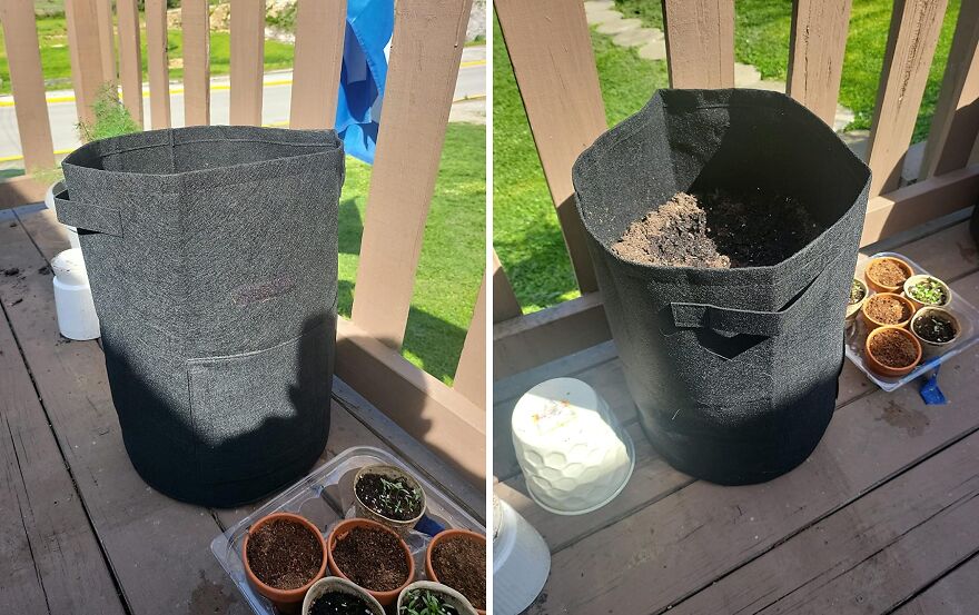 Black fabric garden planter bag filled with soil and small pots of seedlings on a wooden deck outside.
